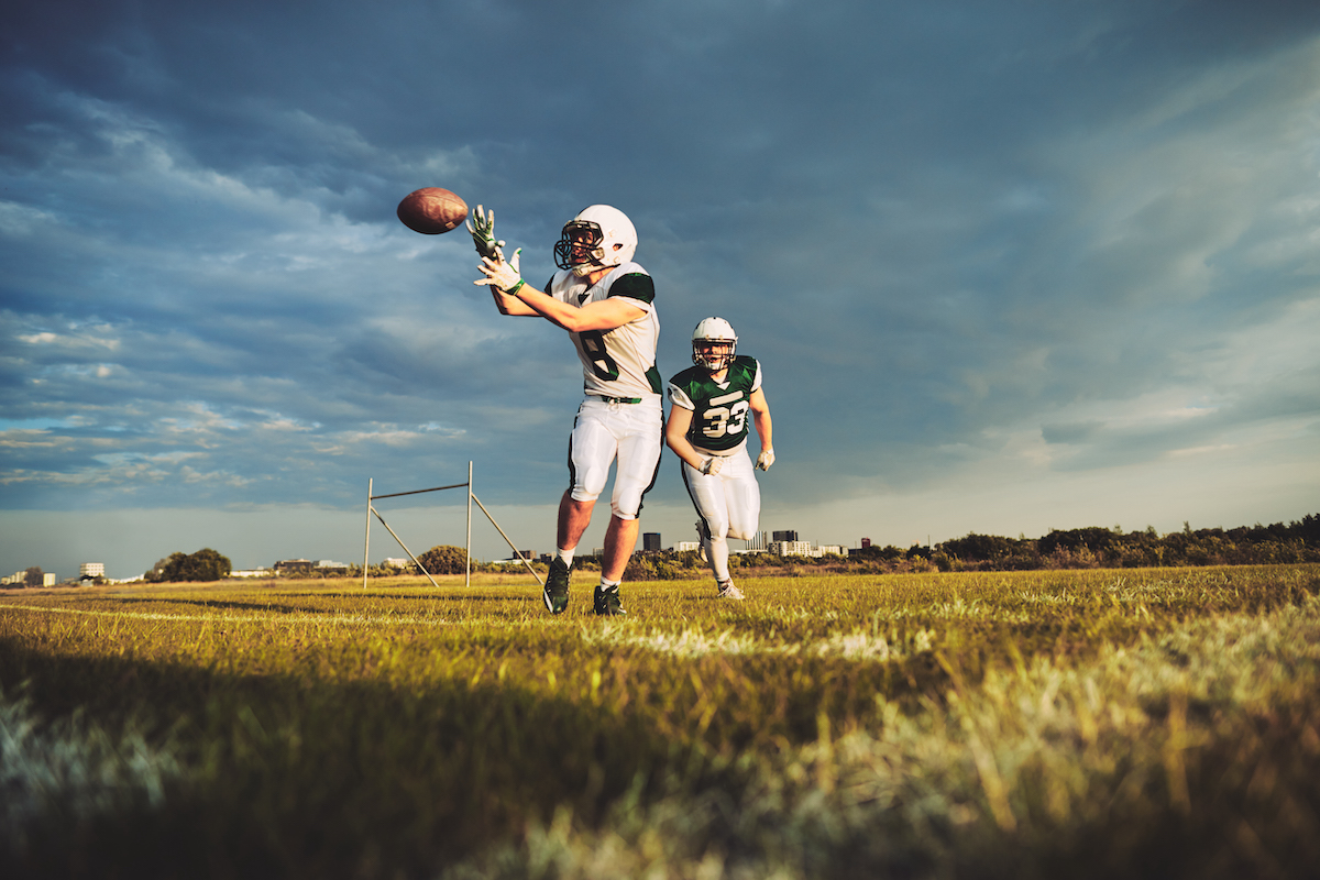 American football player catching a pass during team drills