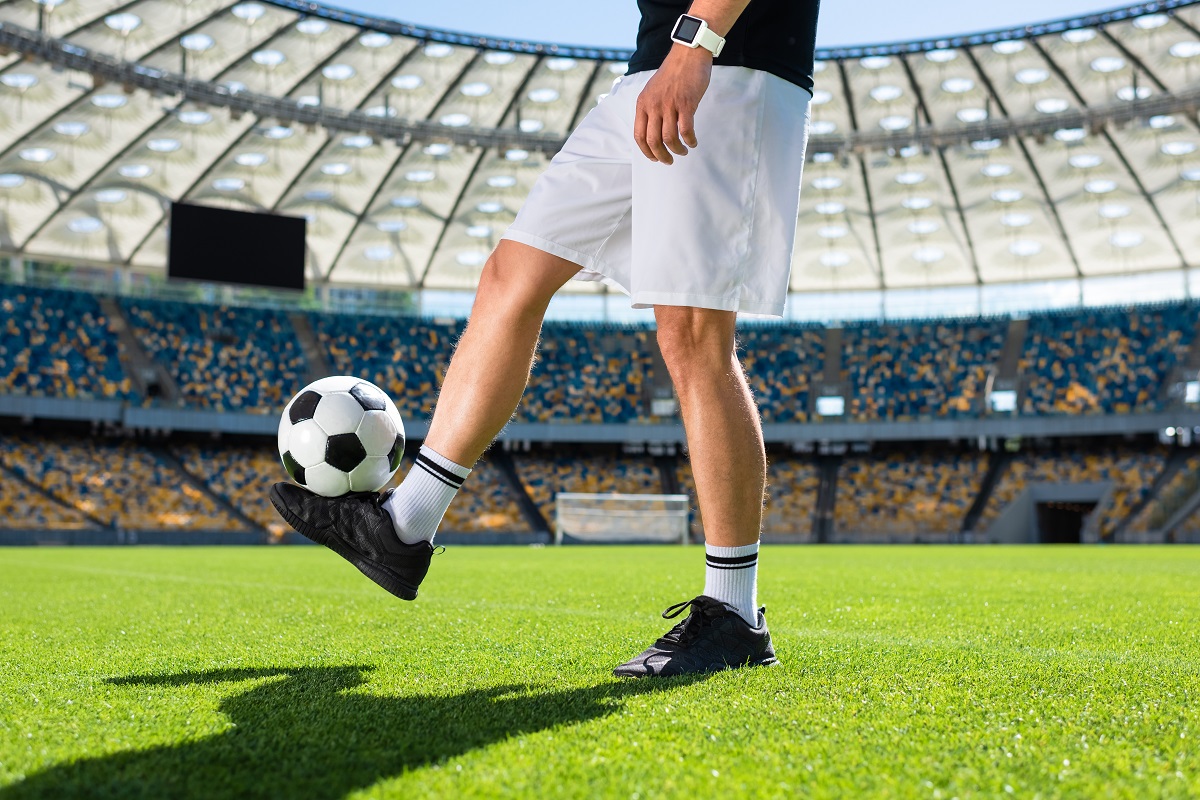 cropped shot of soccer player bouncing ball at sports stadium