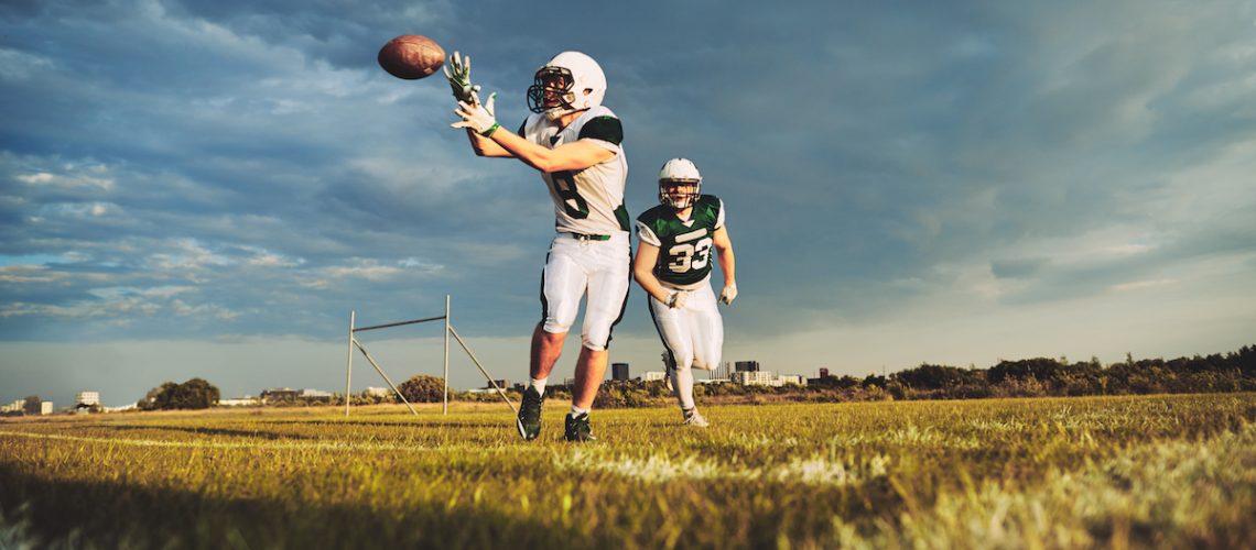 American football player catching a pass during team drills