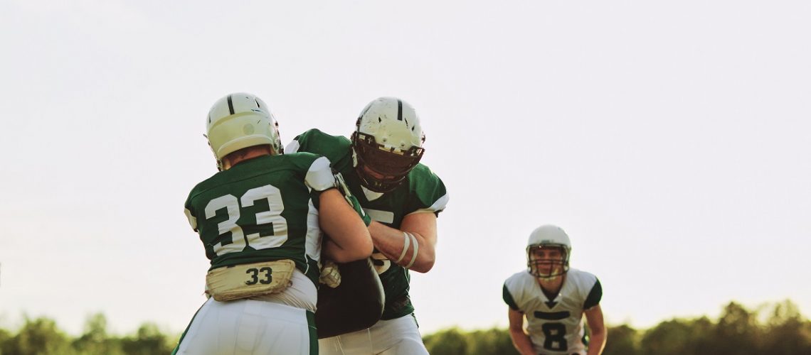 American football players practicing tackling on a sports field