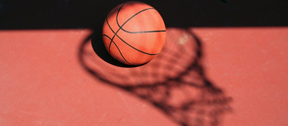 A Basketball and net shadow on a red court