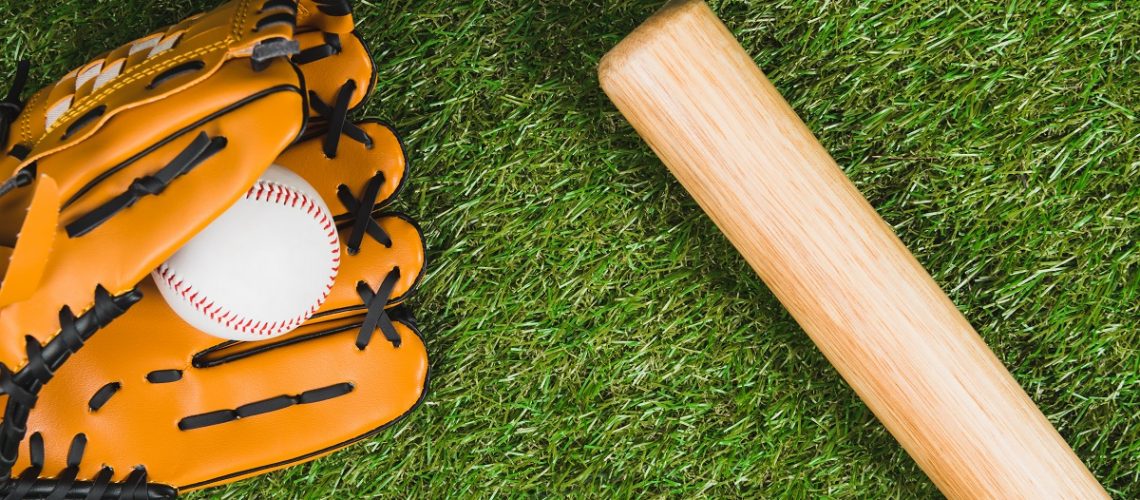 Top view of baseball bat with glove and ball on green grass