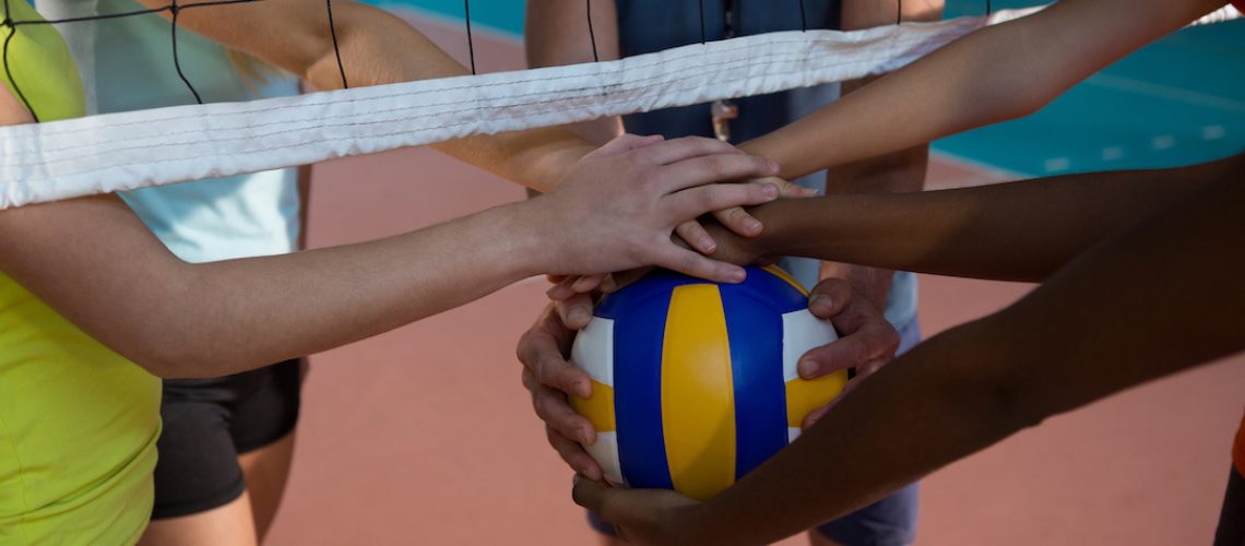 Volleyball team joining hands before practice