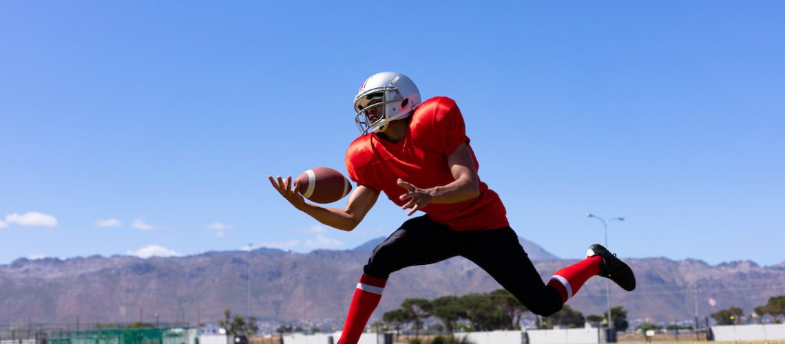 Football player gaining control of the ball as he runs