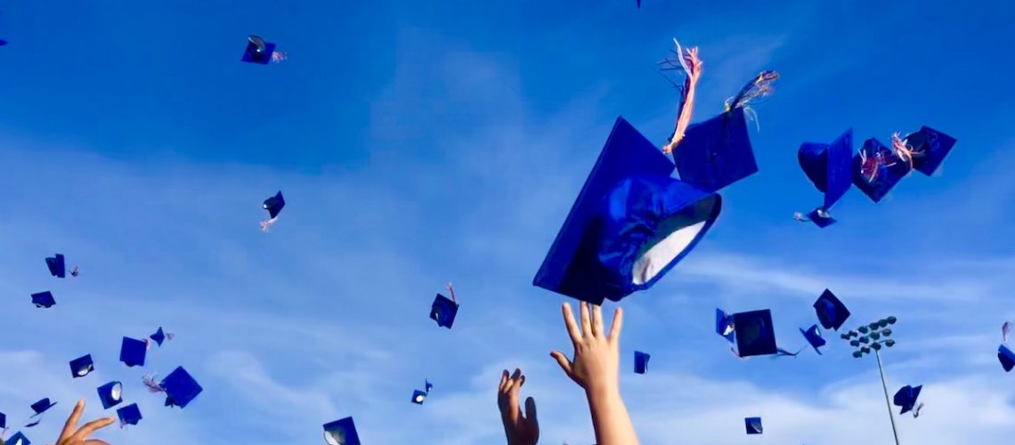 Graduates tossing their blue, square hats