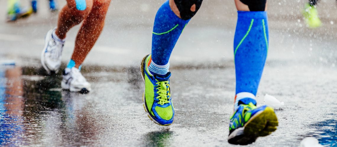 Legs of runners using kinesiology tape and compression socks