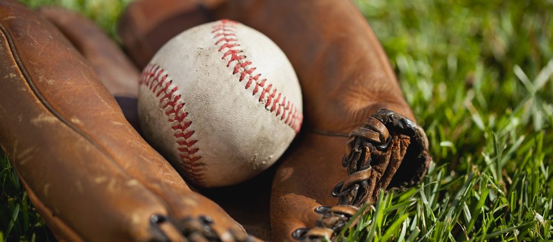 Vintage baseball mitt with an old ball in the grass