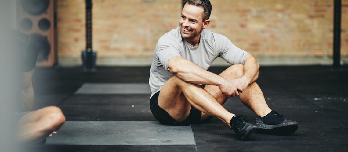 Smiling man sitting on a gym floor after working out