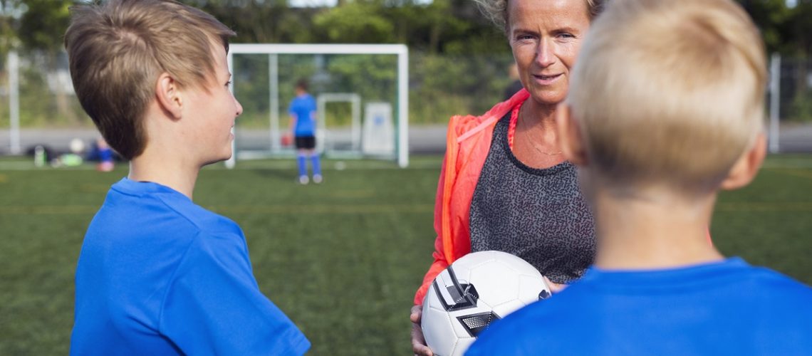 Mother with sons (10-11, 12-13) in soccer field