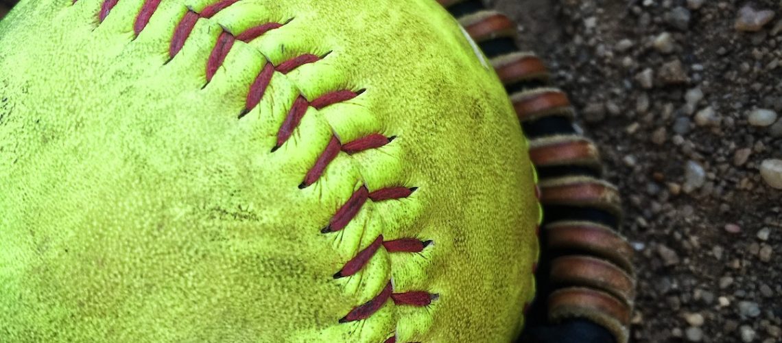 Up close shot of softball and glove on the infield dirt