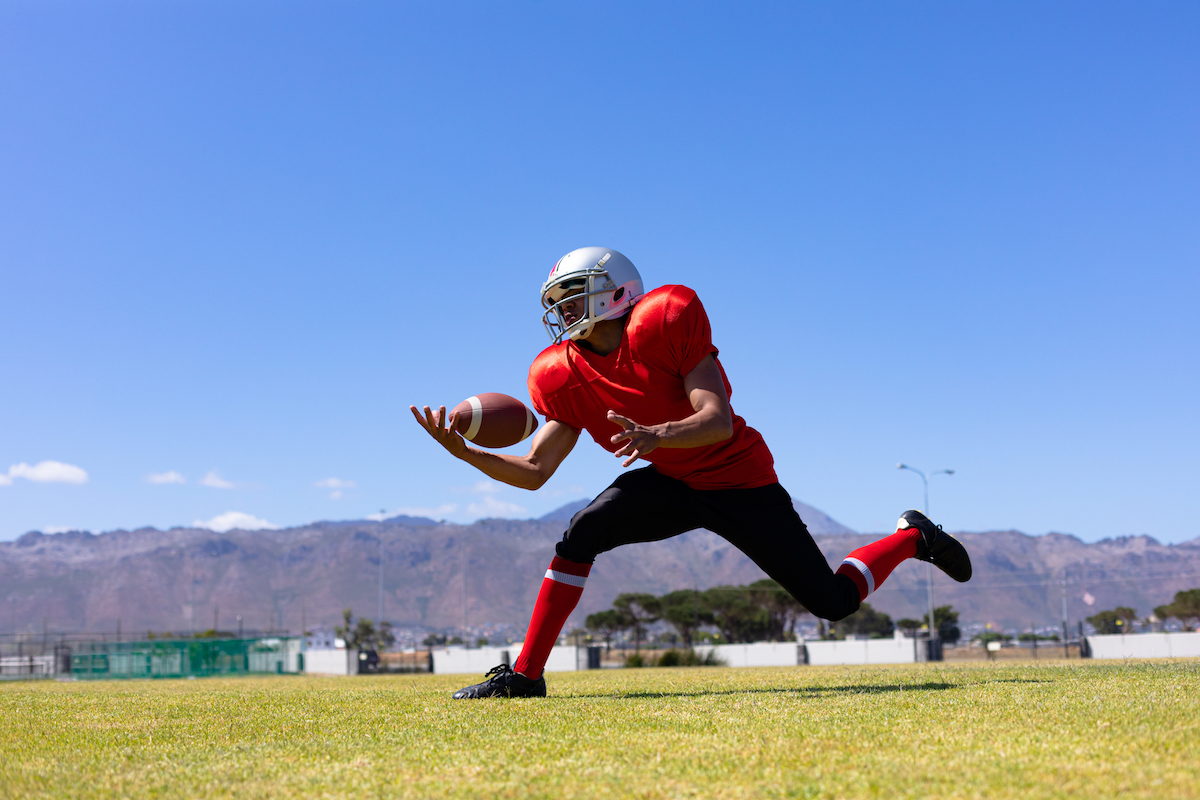 Football player gaining control of the ball as he runs