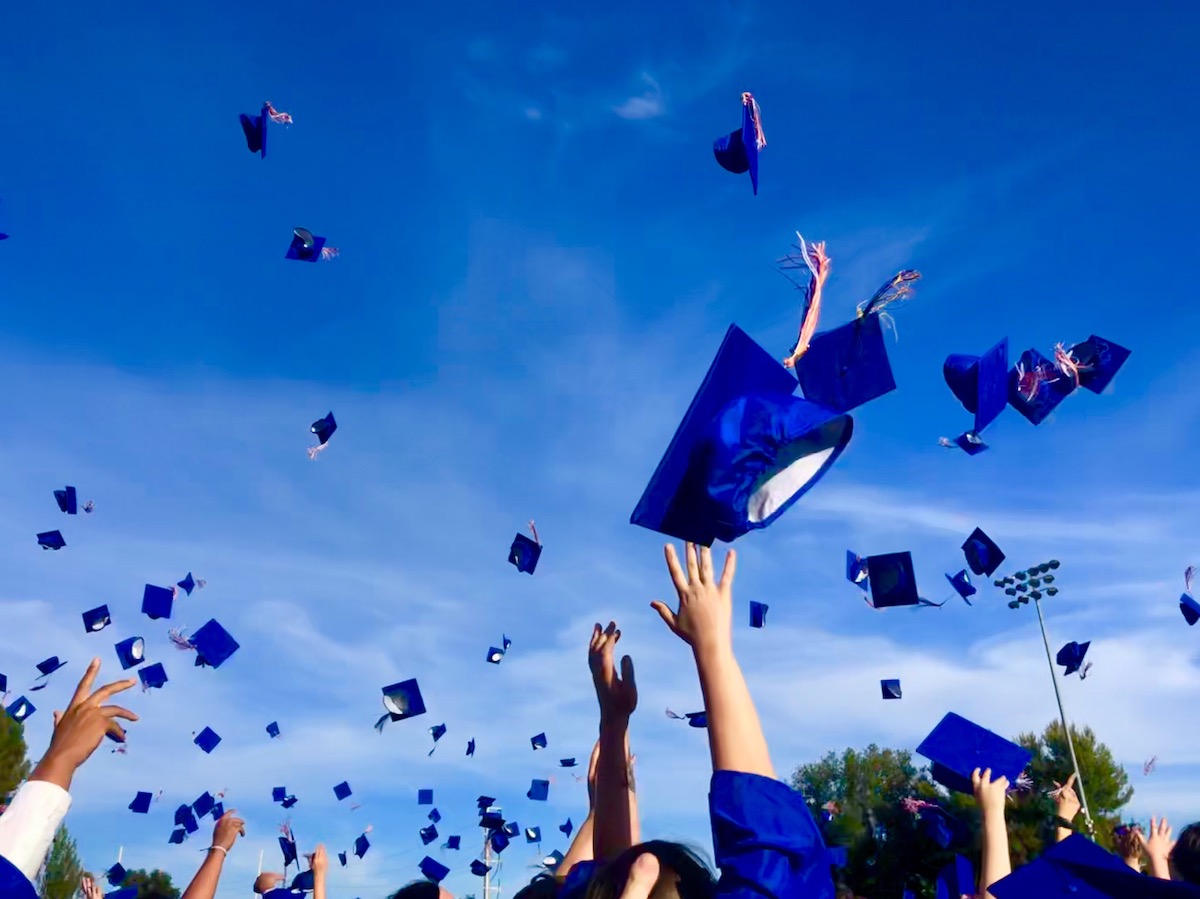 Graduates tossing their blue, square hats