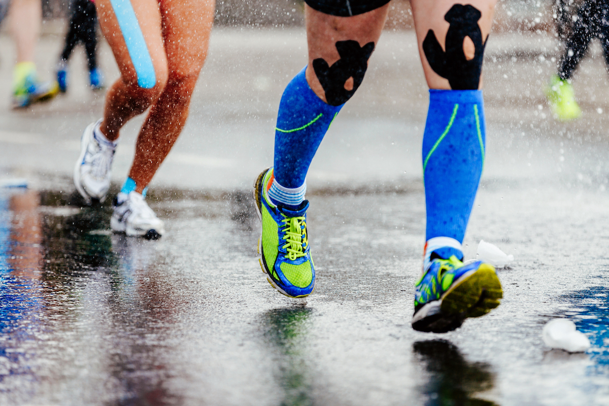 Legs of runners using kinesiology tape and compression socks