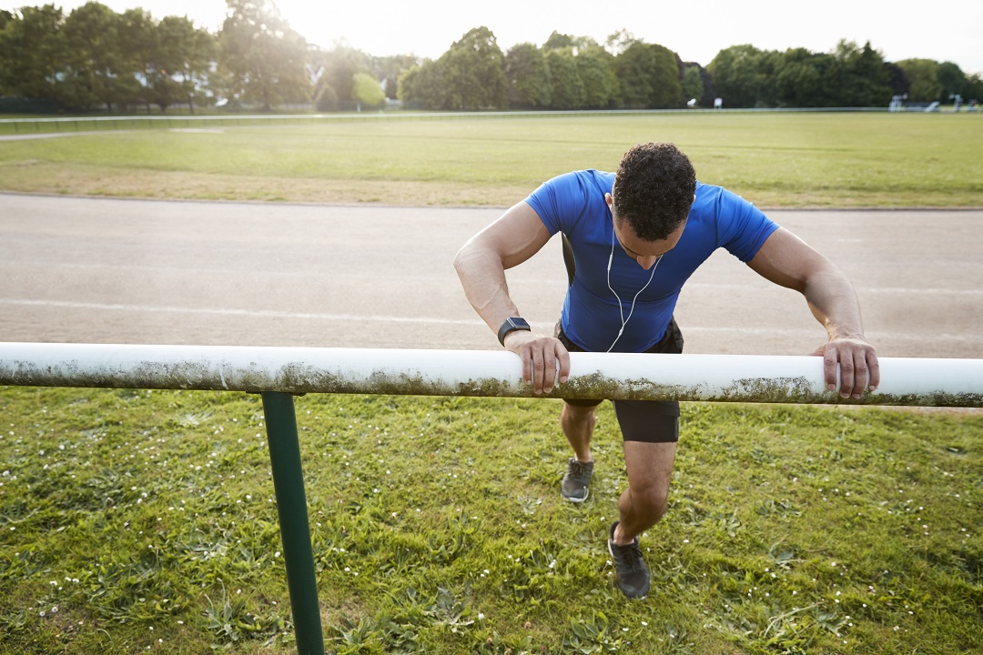 Male athlete stretching at running track, close up