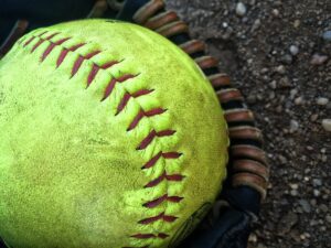 Up close shot of softball and glove on the infield dirt